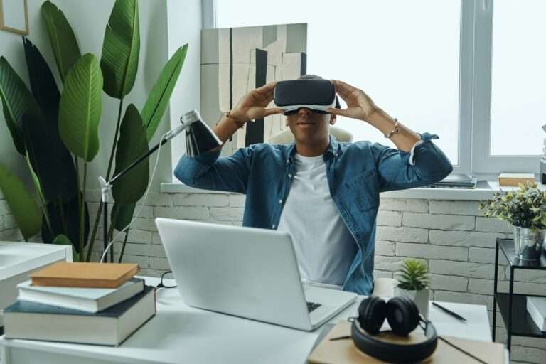 Young mixed race man wearing virtual reality glasses while sitting at working place